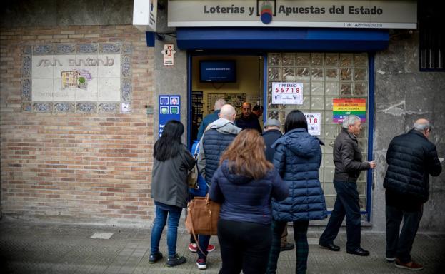 Imagen principal - Las colas son la estampa habitual en este despacho de lotería. Ainhoa Asenjo muestra el boleto que le ha comprado a su madre. Abajo, Josean, uno de los loteros, coloca un cartelote del sorteo del Gordo.