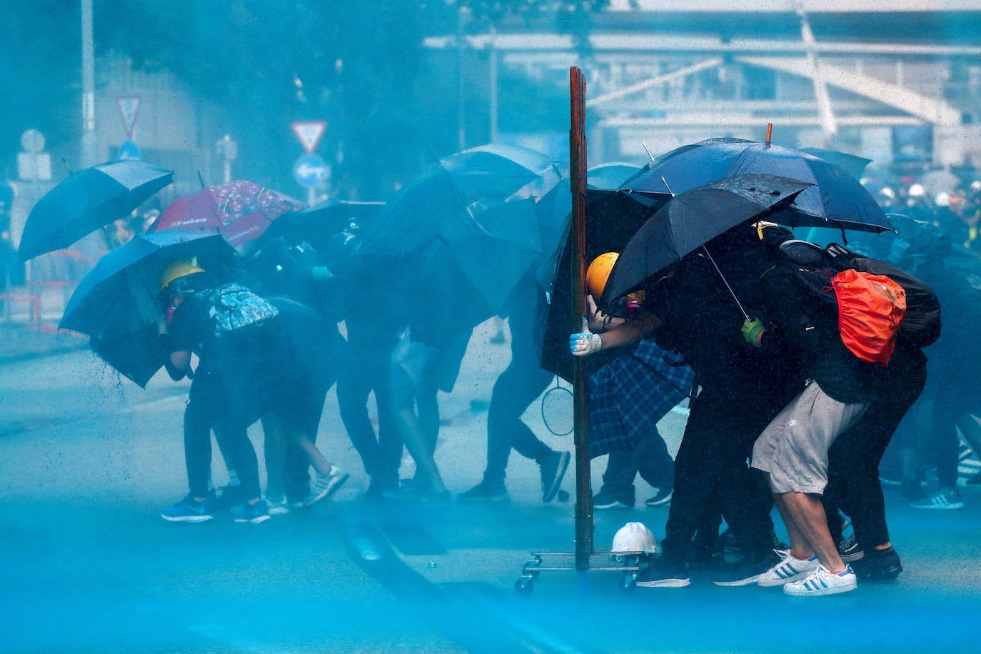 Hong Kong | Los manifestantes se cubren con sombrillas mientras son rociados con agua de color azul durante una manifestación cerca del edificio del Consejo Legislativo, 29 de septiembre de 2019. 