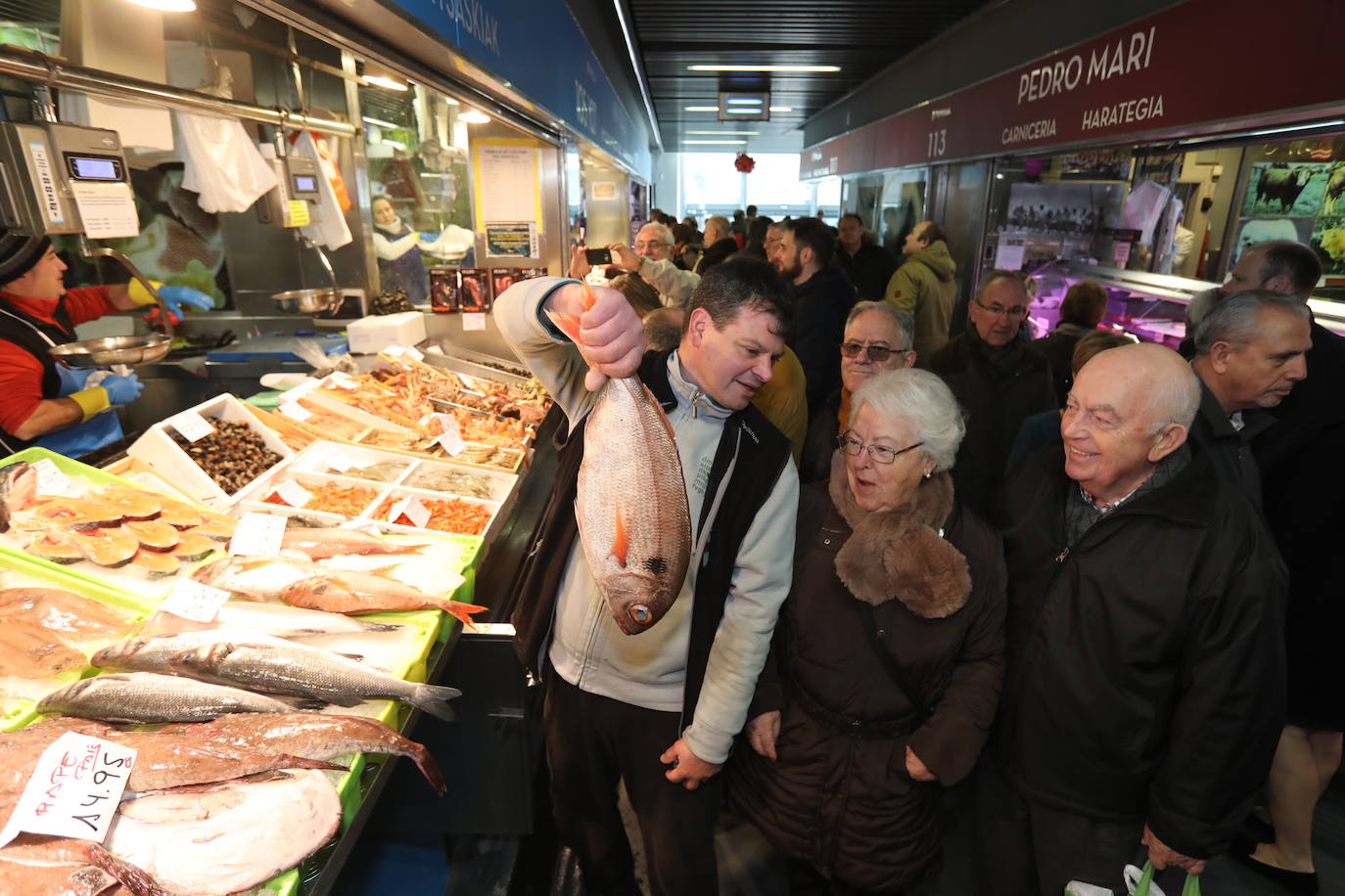 Una pareja observa asombrada el pescado que le muestra un dependiente en el mercado de la Rivera.