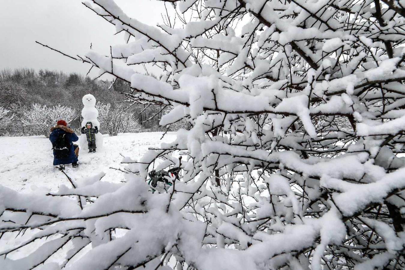 Un hombre y su hijo con un muñeco de nieve en un parque en Moscú