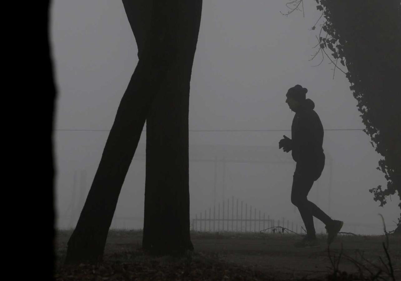 Un hombre realiza ejercicio en un parque bajo un manto gris debido a los altos niveles de contaminación en Belgrado, Serbia