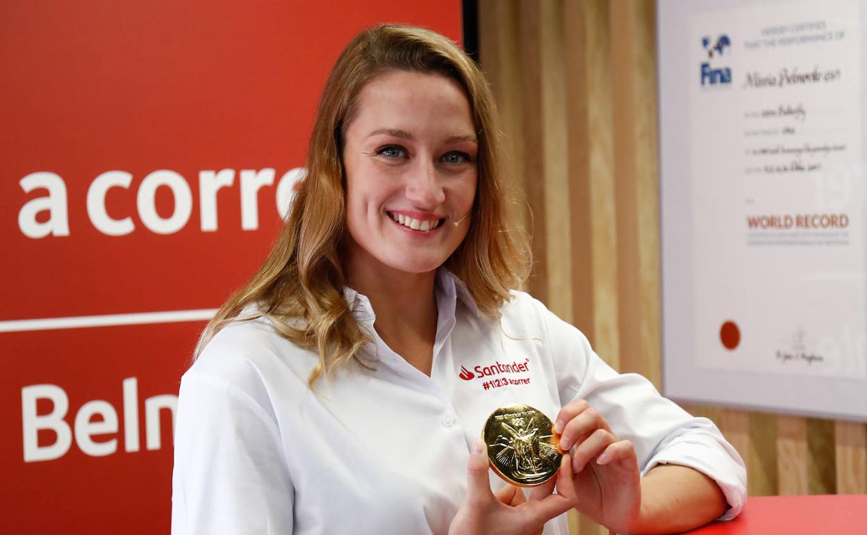 Mireia Belmonte posando con una de las numerosas medallas que ha ganado,  en la inauguración de su exposición en Madrid. 