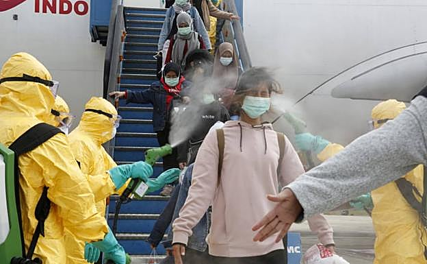 Pasajeros de un avión son rociados de desinfectante al desembarcar.