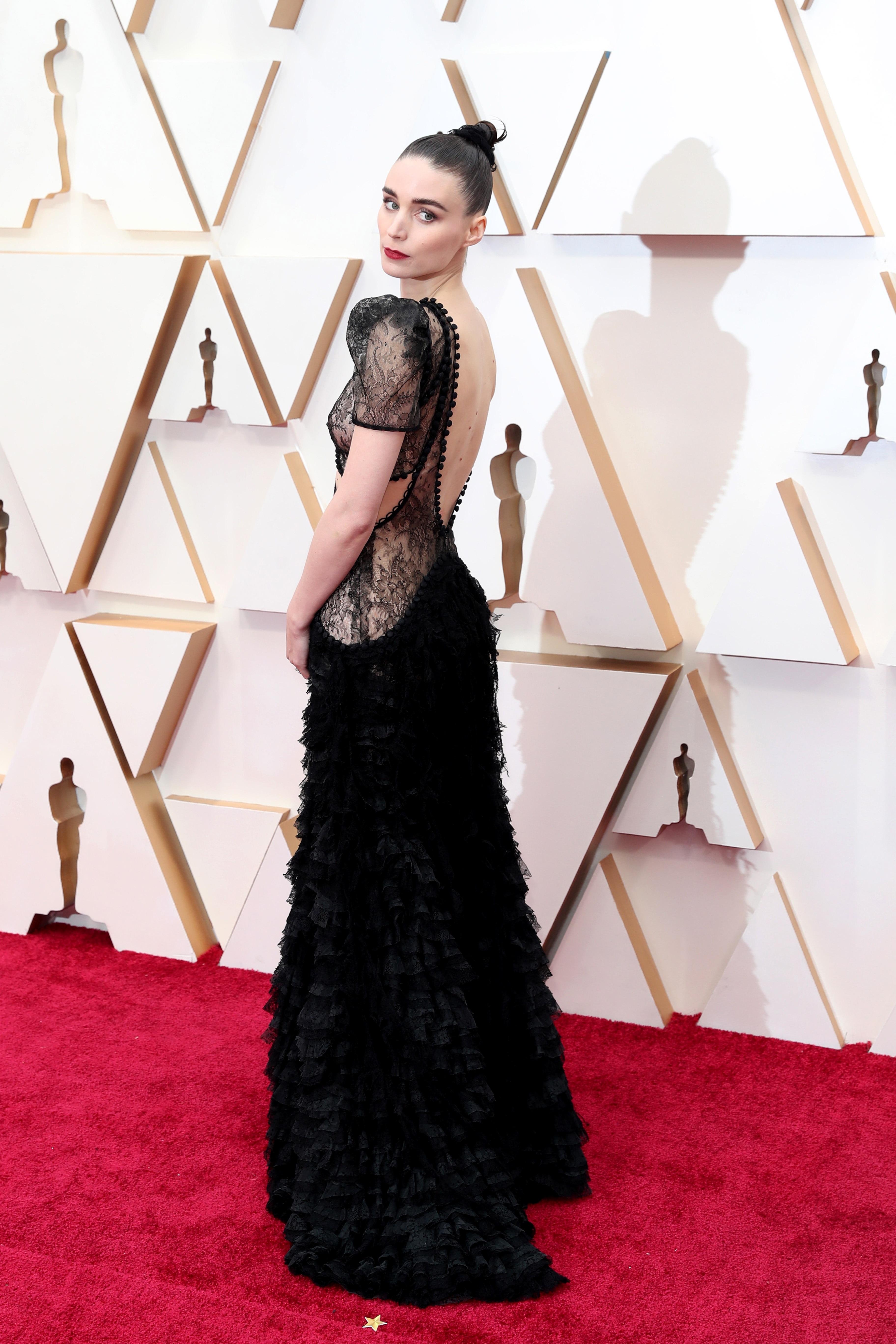 Rooney Mara, como es habitual, vuelve a apostar por el negro y consigue hacerlo especial a base de bordados que parecen una segunda piel. Y es que ha elegido un diseño de Alexander McQueen con un cuerpo semitransparente de mangas abullonadas y ‘cut-outs’ estratégicos que compensa con una falda de microvolantes.