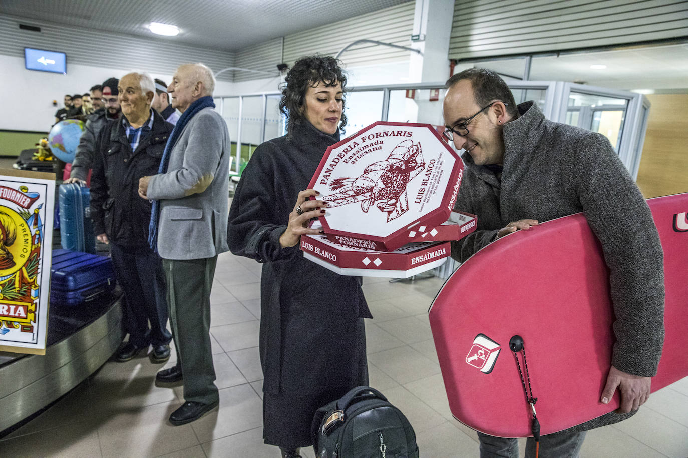 Rocío López, presidenta de la Sociedad Fotográfica Alavesa, muestra una caja de ensaimada al librero Diego Martínez de San Vicente, presidente de Gasteiz On, que sujeta una minitabla de surf.