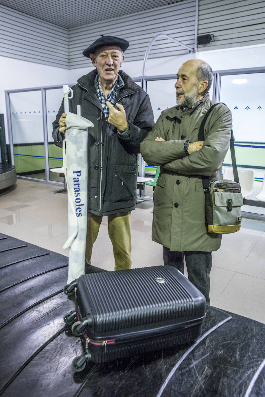 Javier Cameno espera su equipaje junto a Josemari Vélez de Mendizabal, de los Celedones de Oro.