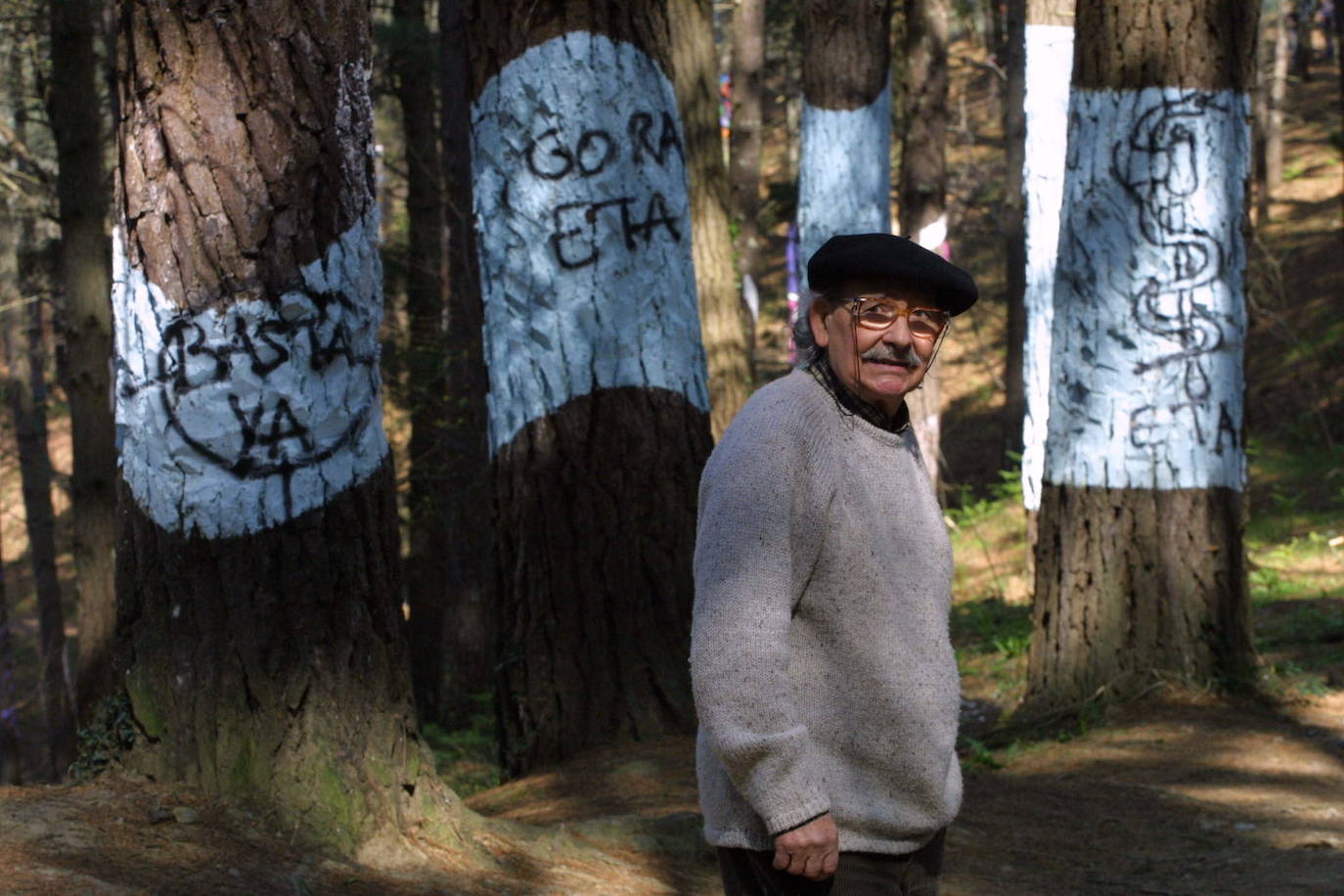 Agustín Ibarrola posa junto a las pintadas amenazantes aparecidas en el bosque de Oma en marzo de 2003. 