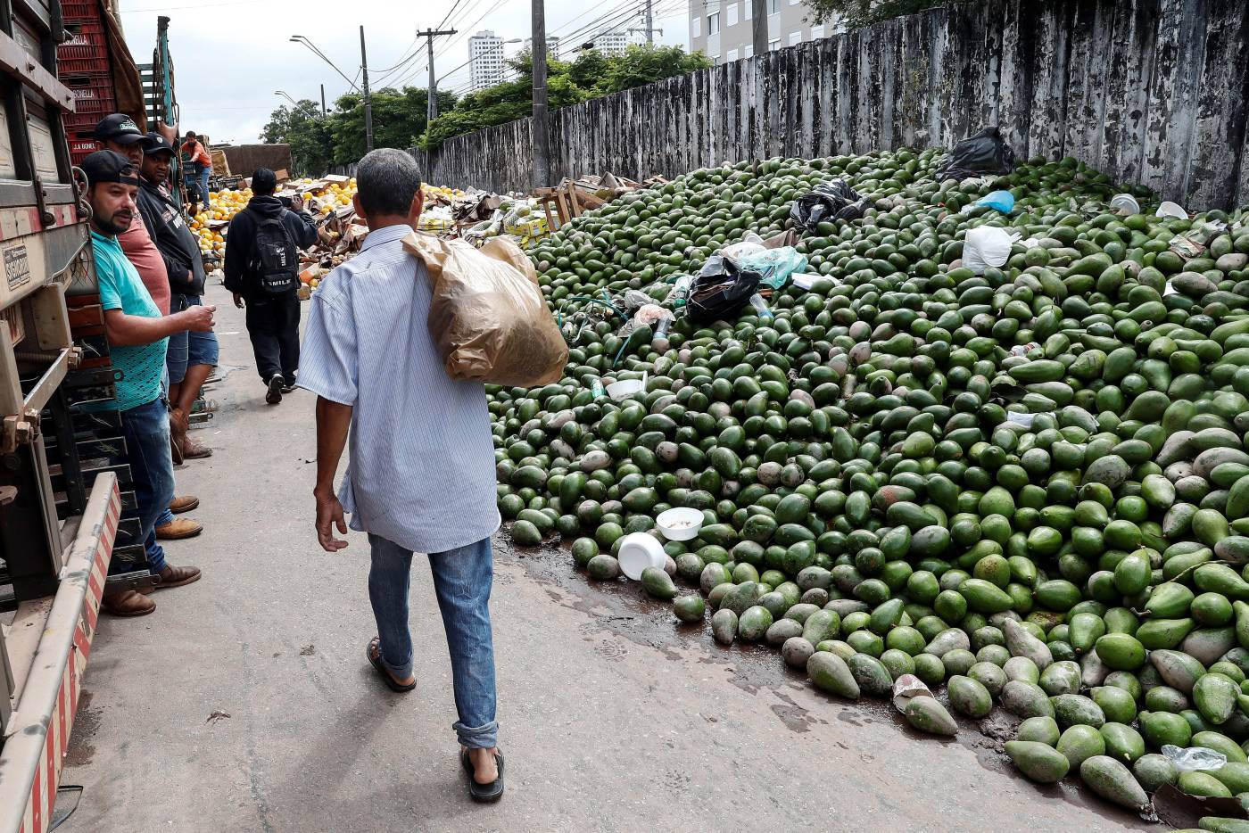 Personas descartan frutas, verduras y legumbres, llenas de lodo como consecuencia del fuerte temporal, en la Central de Abastos, que arreció sobre Sao Paulo provocando el desbordamiento del río Pinheiros, en la ciudad de Sao Paulo (Brasil ) 