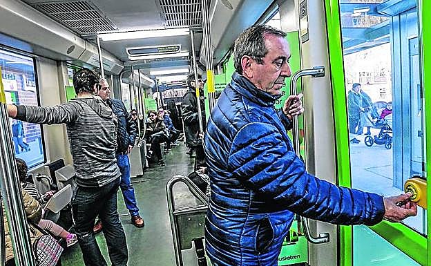 Un viajero pulsa el botón para descender en la parada de Hegoalde.