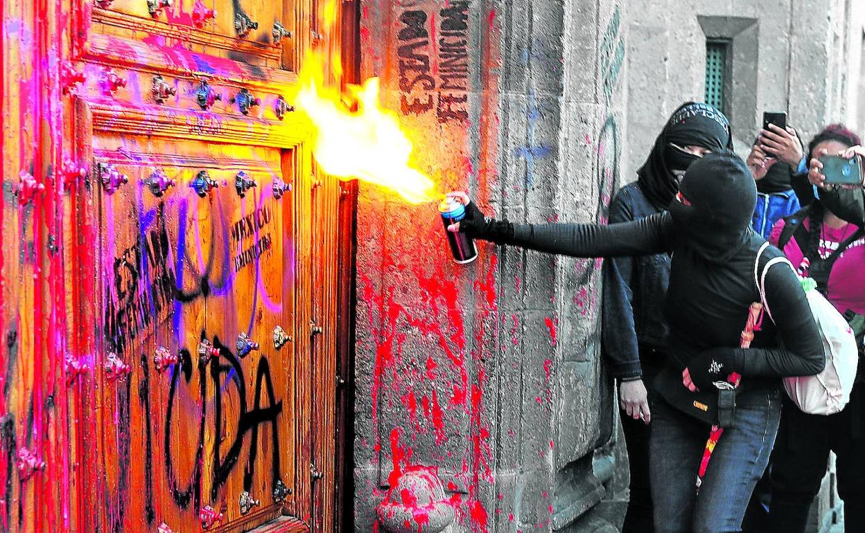 Unas manifestantes queman una de las puertas del Palacio Nacional, plagada de pintadas, durante las protestas. 