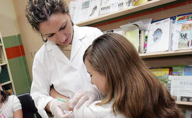 Una enfermera vacuna a una niña en un colegio. 