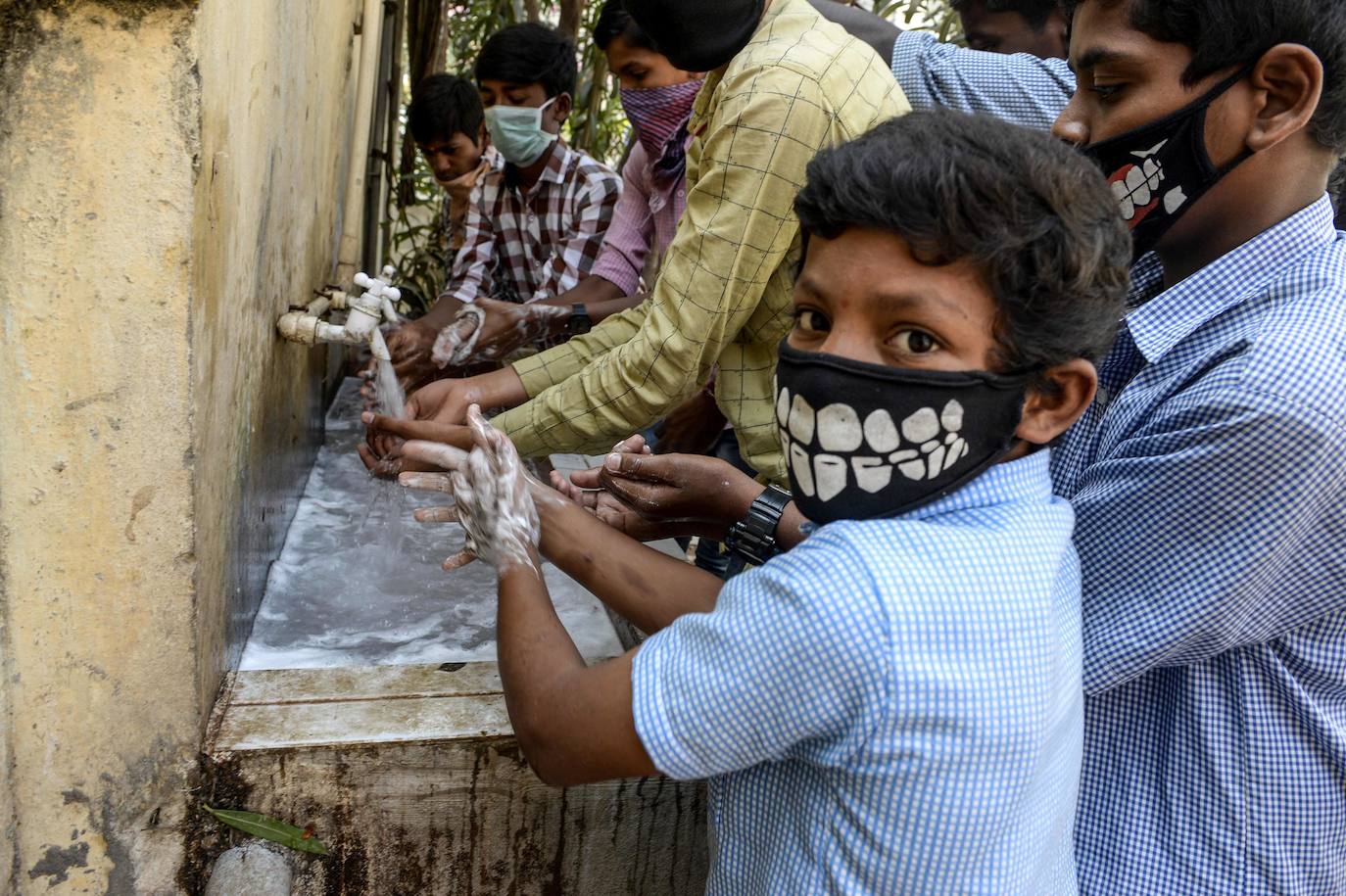 Estudiantes con mascarillas se lavan las manos antes de asistir a una clase en una escuela en Secunderabad.