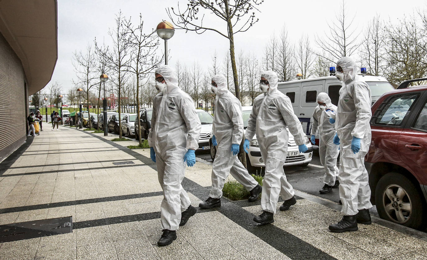 Agentes de la Ertzaintza entregan órdenes de confinamiento en un portal de Vitoria. 