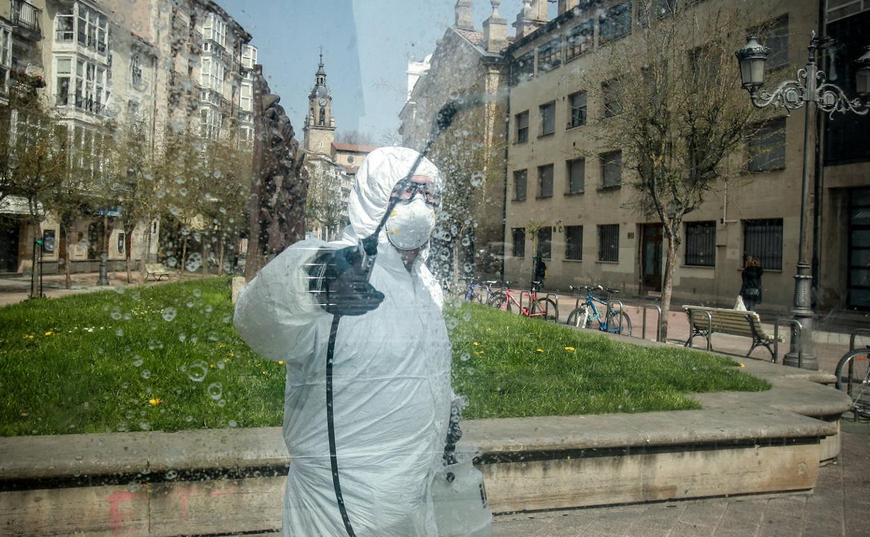 Un operario desinfecta la parada del tranvía de Parlamento, en el centro de Vitoria.