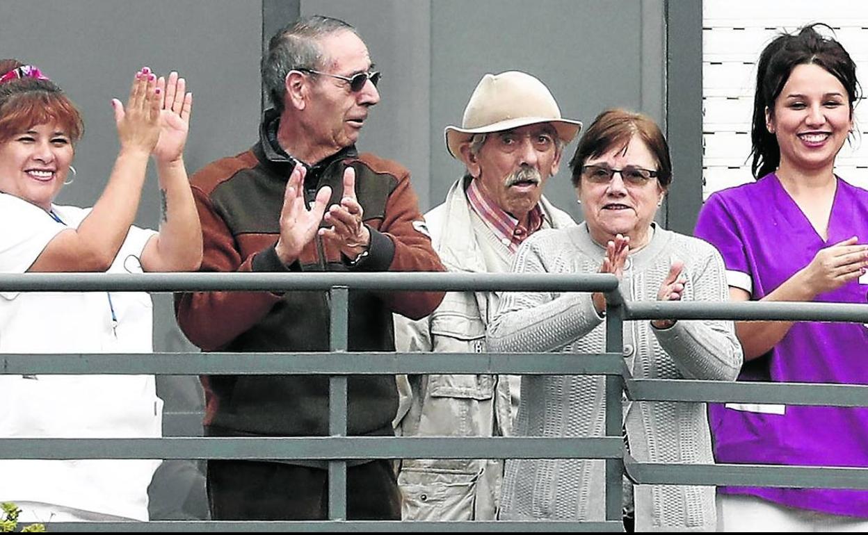 Trabajadoras y usuarios del centro residencial salen a la terraza de las instalaciones para saludar a las personas que les animan desde fuera.