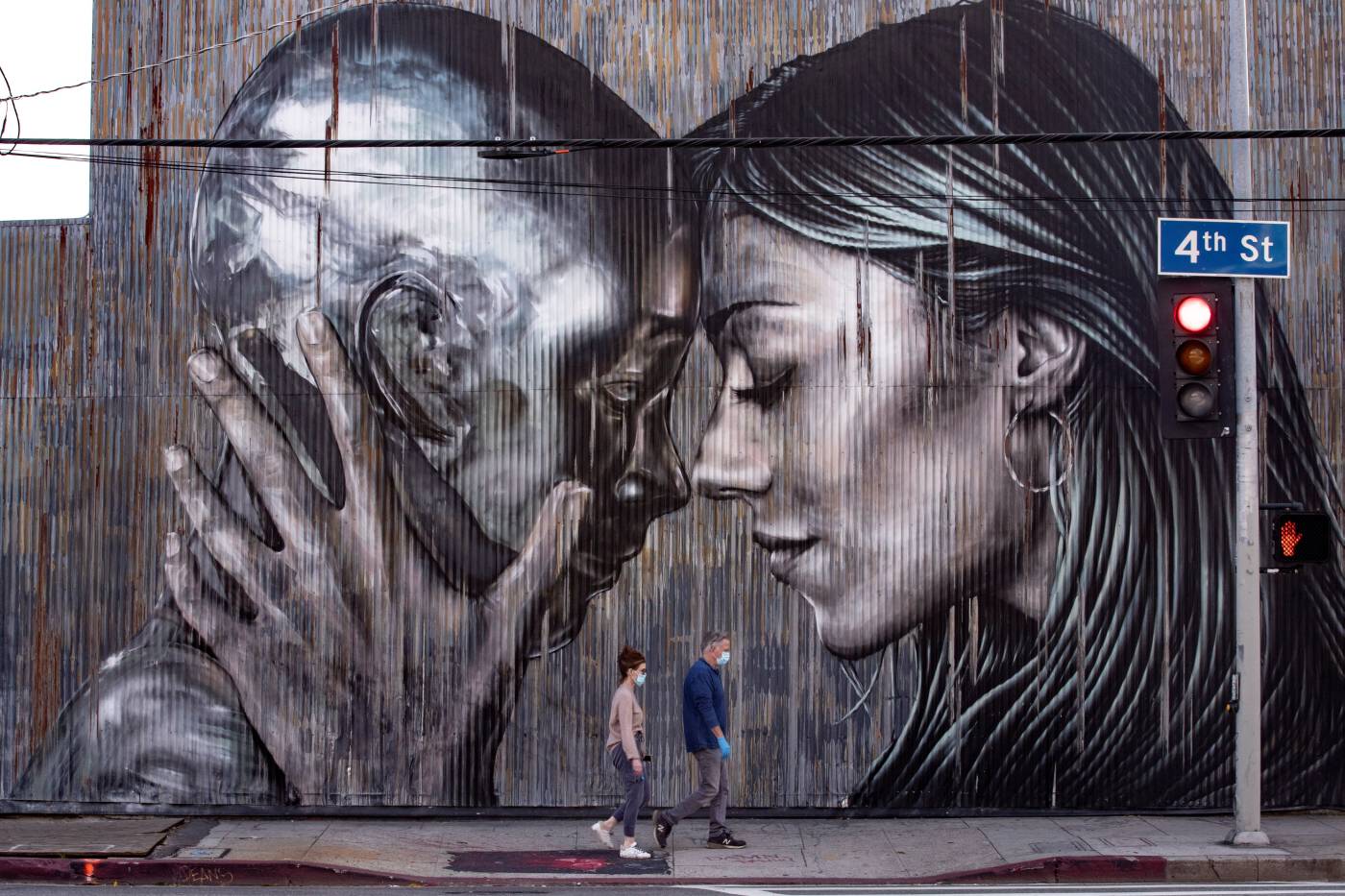 Una pareja pasea junto a un mural en el Distrito de las Artes en Los Ángeles, Estados Unidos, durante la crisis sanitaria causada por el coronavirus.