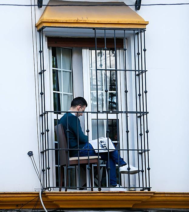 Un joven lee en un balcón.