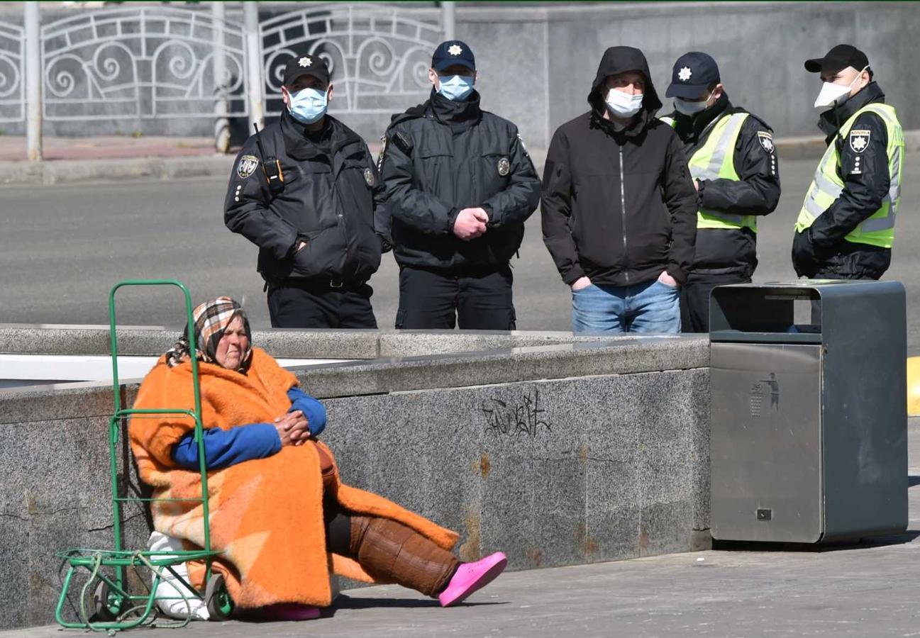 Una anciana sin hogar pide limosna junto a la policía en Kiev, Ucrania 