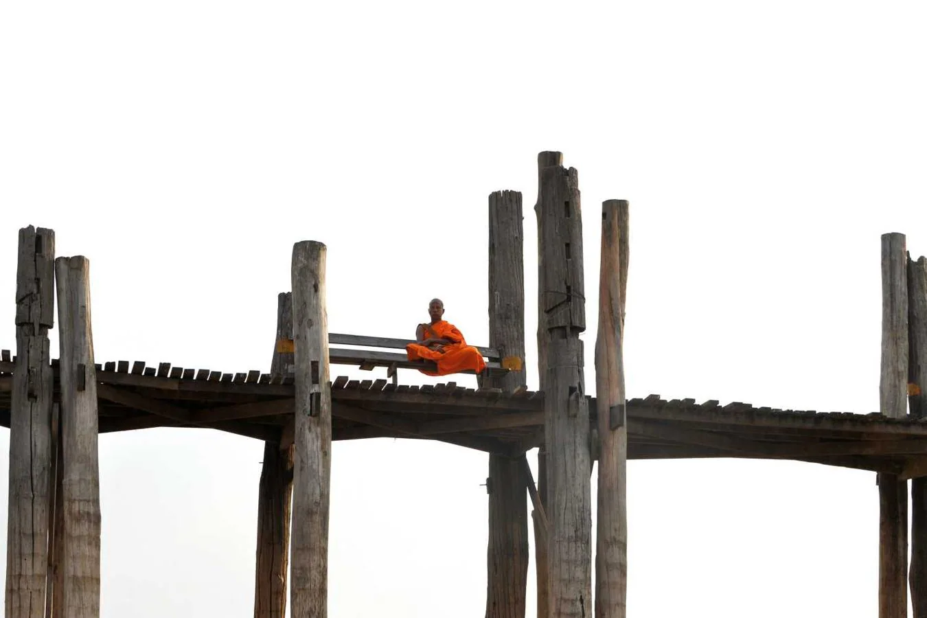 Un monje sentado en el puente U Bein en Mandalay, Birmania 