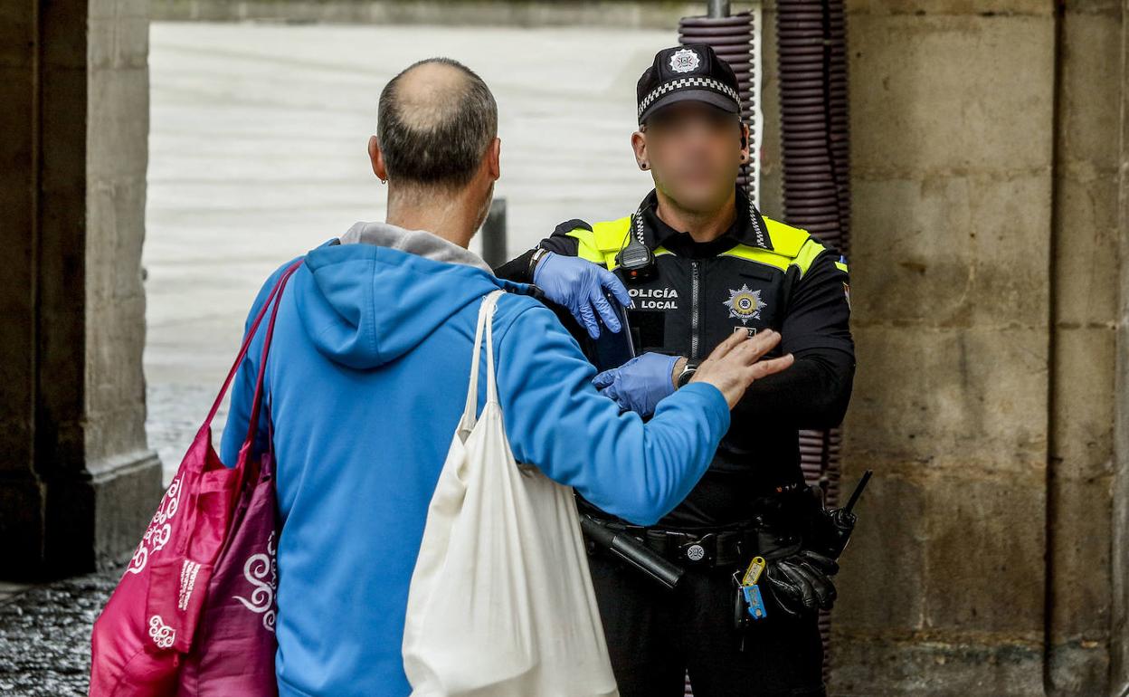 Un policía local conversa con un viandante en una calle de Vitoria. 