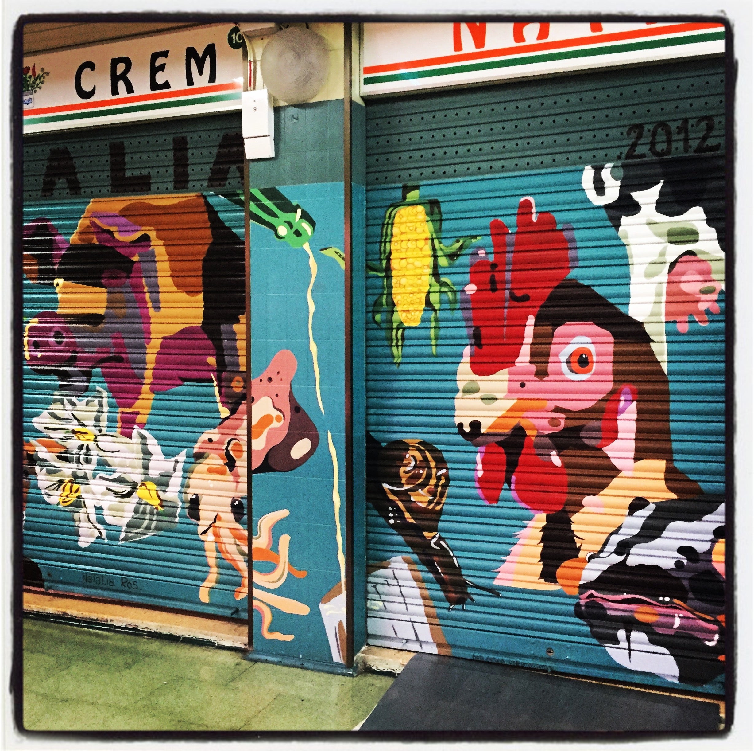 Un llamativo gallo es uno de los protagonistas pintados en esta persiana de un comercio de alimentación ubicado en el interior del mercado de la Avenida Gasteiz.