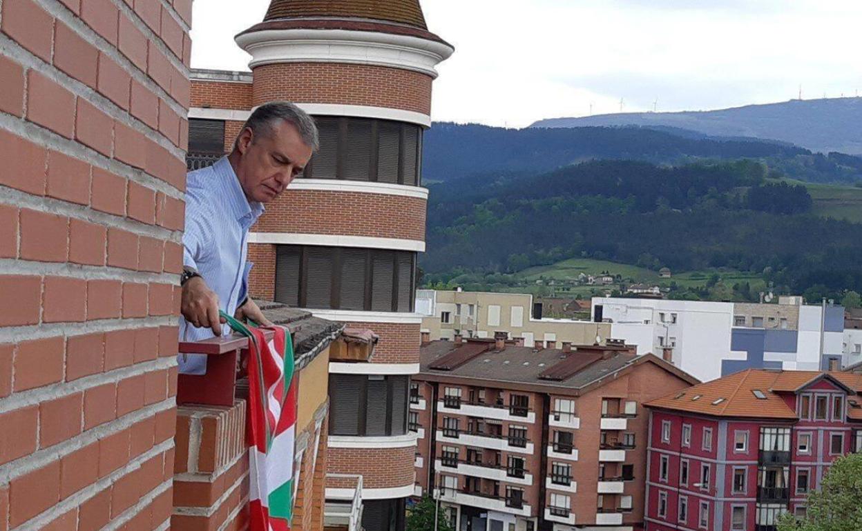 Urkullu cuelga la ikurriña del balcón de su casa de Durango. 