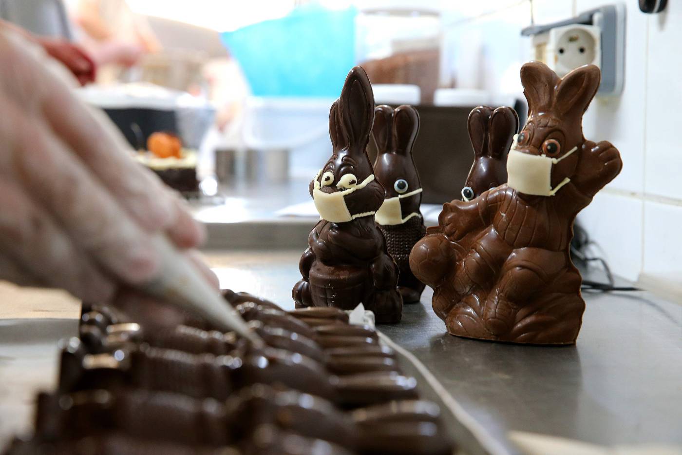 Un fabricante de chocolate termina conejos de chocolate de pascua con una máscara facial, en Troyes en medio de la propagación de la enfermedad COVID-19 causada por el nuevo coronavirus.