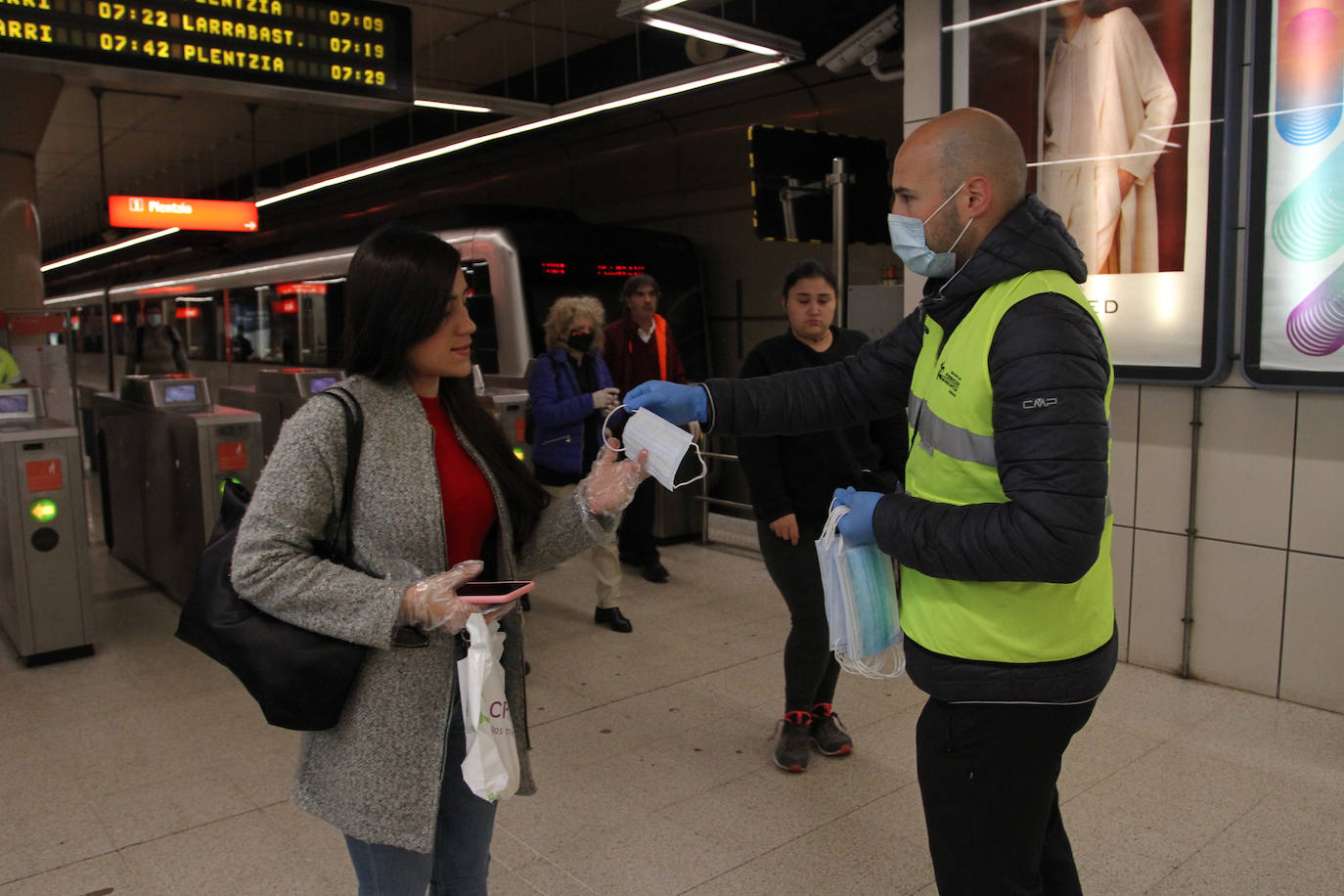 Un voluntario de la DYA entrega mascarillas a la entrada de la estación de La Arenas.