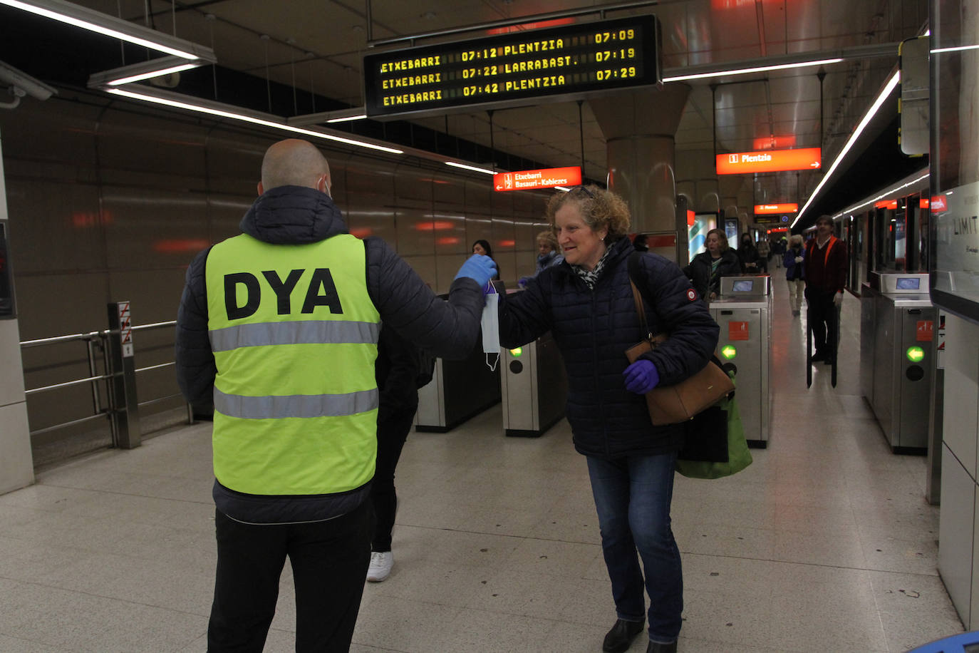 Un voluntario de la DYA entrega mascarillas a la entrada de la estación de La Arenas.