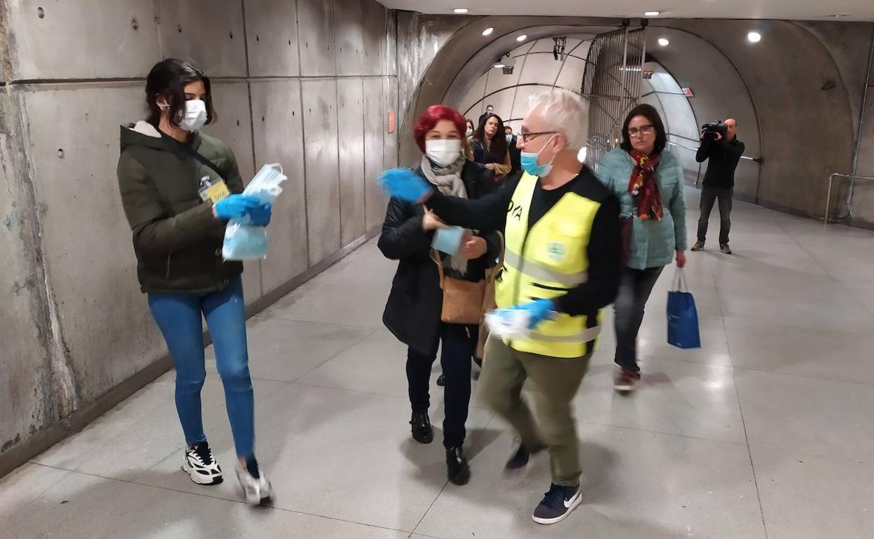 Una voluntaria reparte mascarillas entre los usuarios del metro en Bilbao.