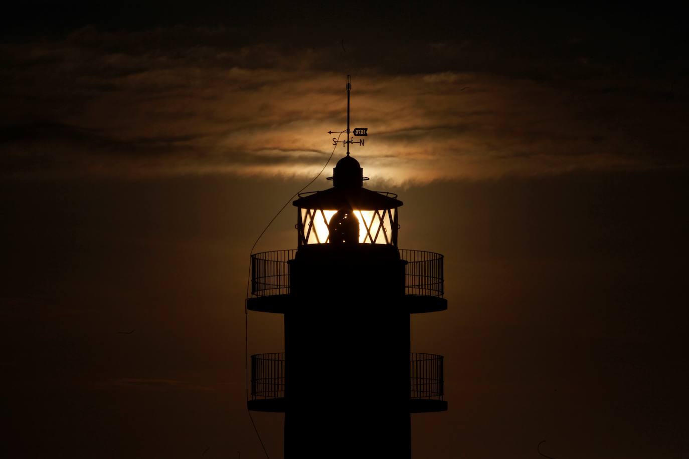 Faro iluminado con la luz del sol durante un aardecer en Finisterre, en Galicia.