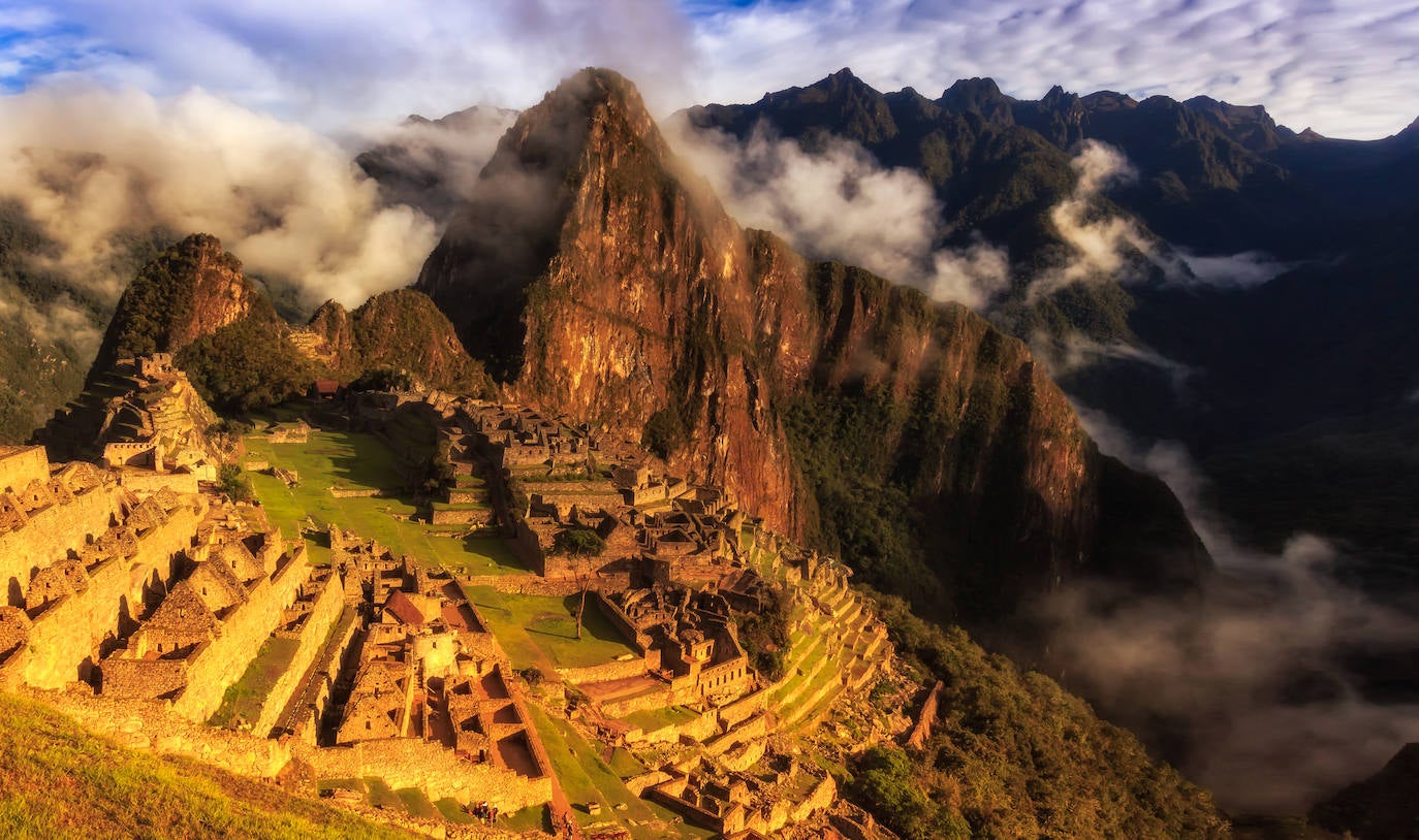 Amanecer en Machu Picchu (Perú). Vista de la ciudad perdida de los incas abajo, a lo largo de la verde llanura aterrazada.