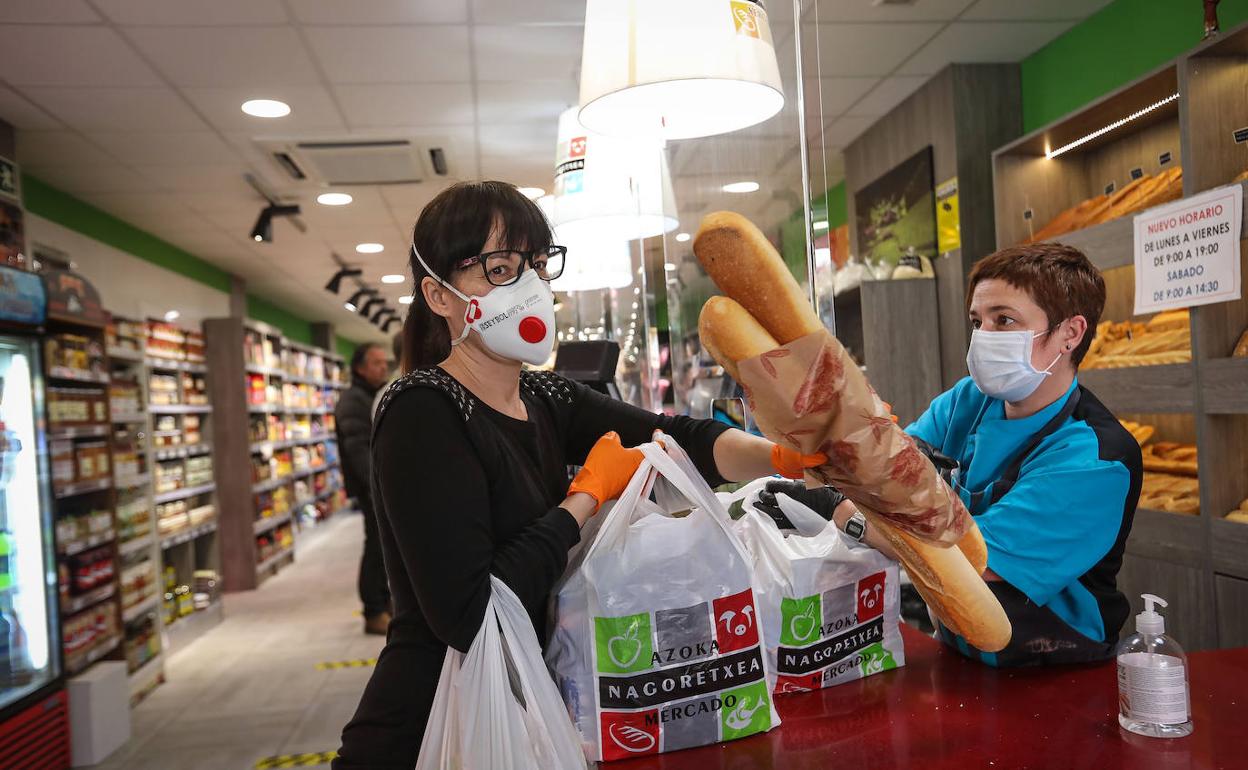 Una trabajadora y una clienta de un supermercado, protegidas del coronavirus con guantes y mascarillas.