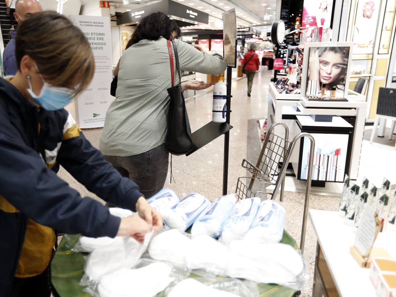 Varias personas cogen mascarillas y geles para los clientes en el Corte Inglés de Bilbao. / Efe