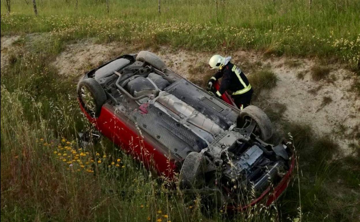 Un bombero, junto al vehículo accidentado.