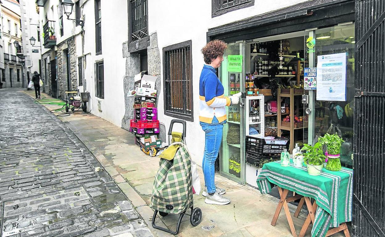 Una mujer espera a la entrada de una tienda de Lekeitio. MAIKA SALGUERO.