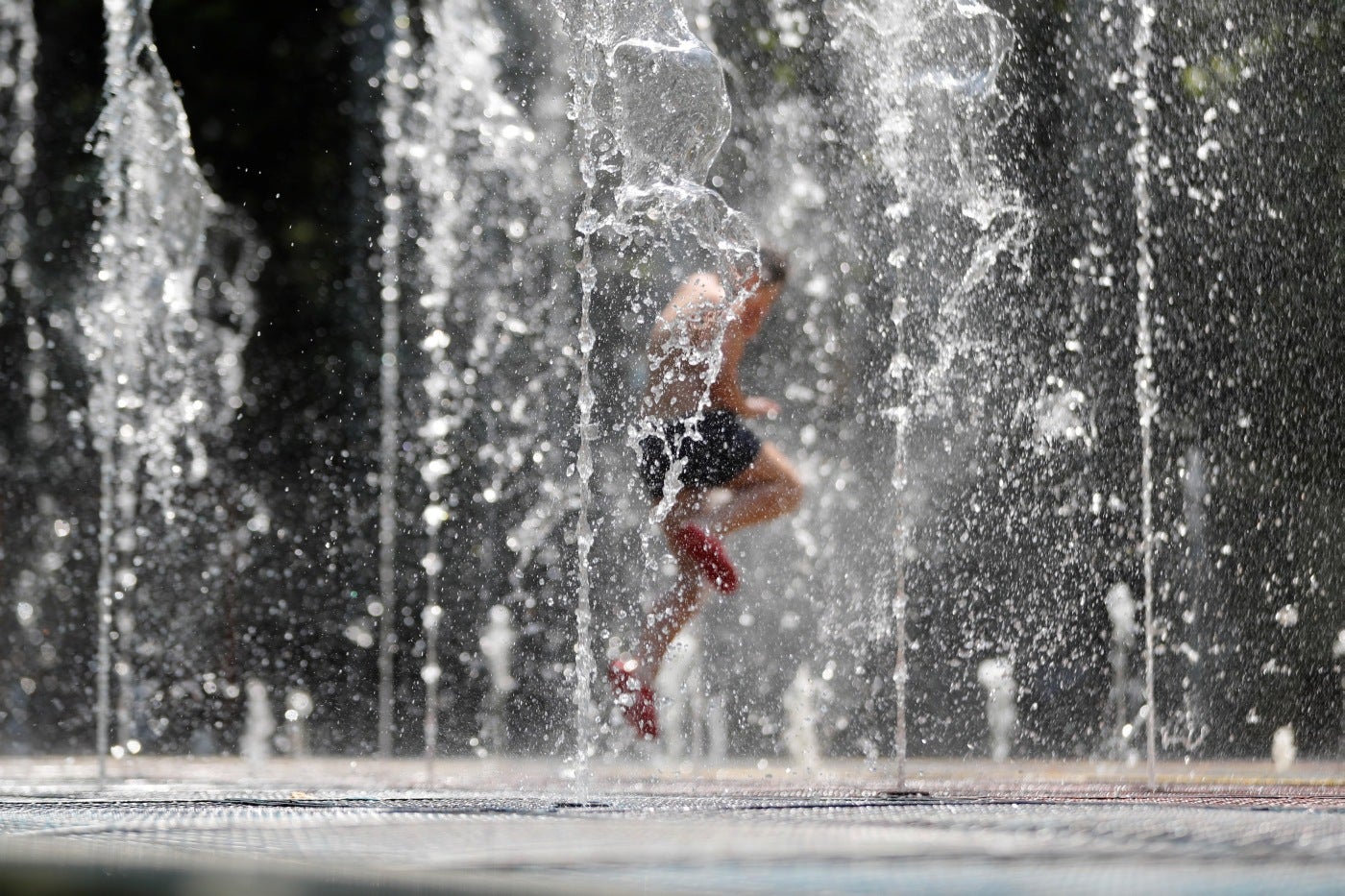 Un niño disfruta corriendo por los chorros de agua de una fuente para refrescarse y escapar del calor del mediodía en Tbilisi, Georgia. Las temperaturas alcanzaron hasta 37 grados centígrados en la capital georgiana. 