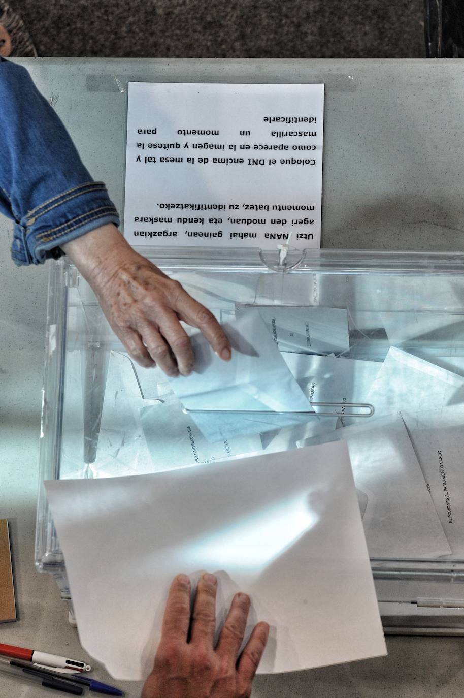 Un ciudadano introduce su voto en la urna de una mesa electoral situada en el centro cívico Ibaiondo.