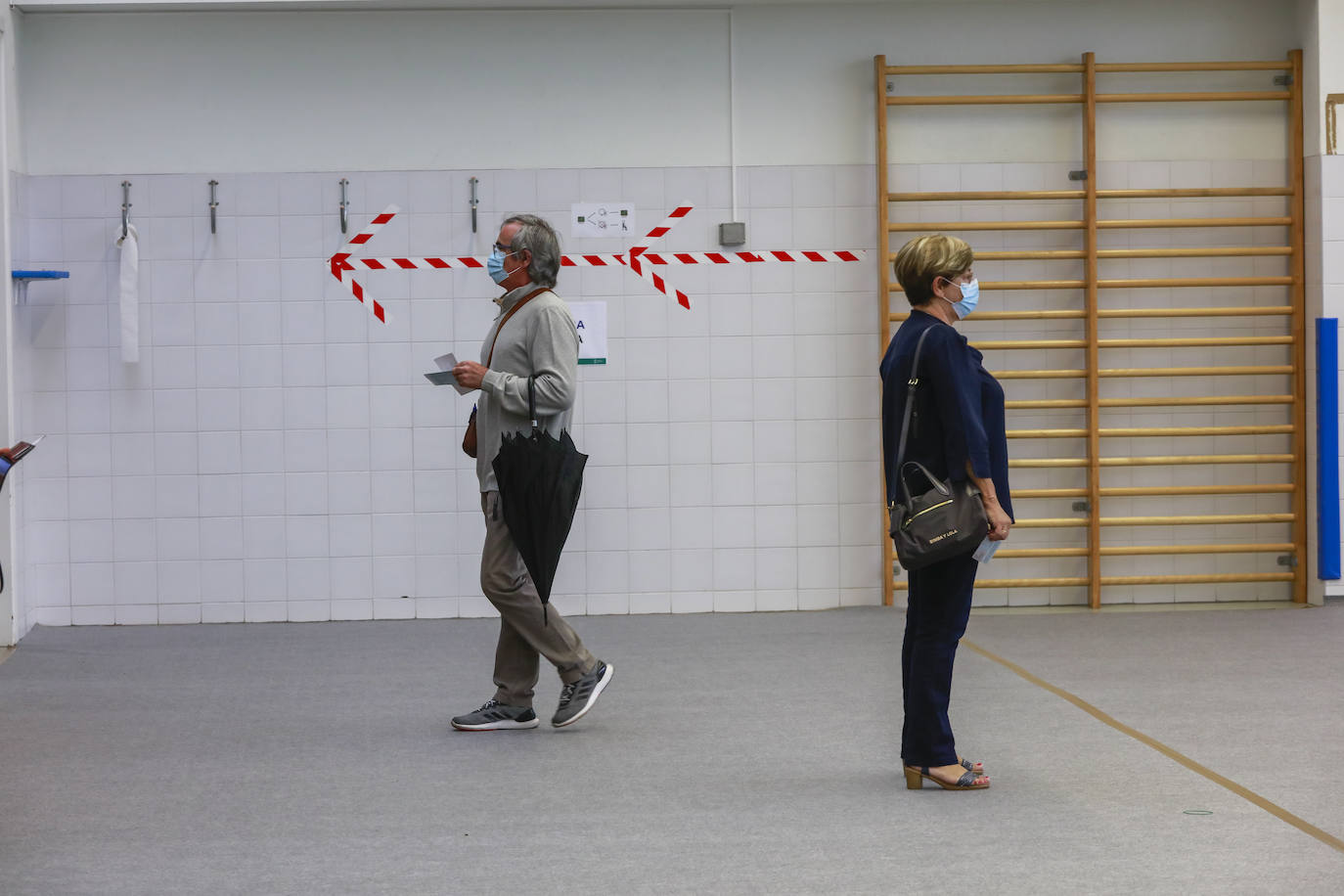 Dos ciudadanos aguardan en la cola su turno para poder depositar su voto en las urnas dispuestas en el colegio de Ibaiondo, en la capital alavesa.
