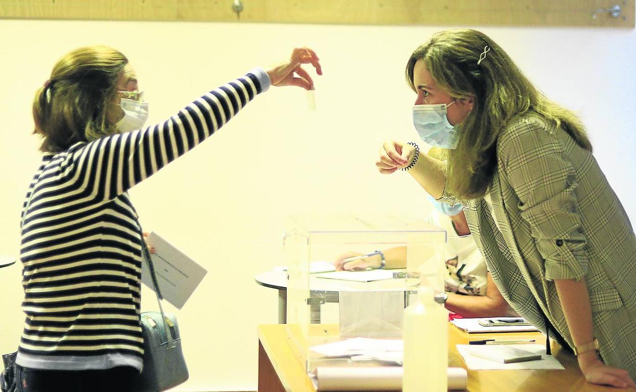 Una votante muestra su identificación a la presidenta de su mesa electoral en el Instituto Unamuno, de Bilbao. 