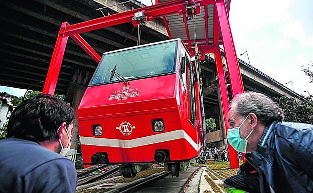 Una grúa de grandes dimensiones eleva el funicular y lo traslada a unos raíles, a pocos metros, para meterlo en el taller. 