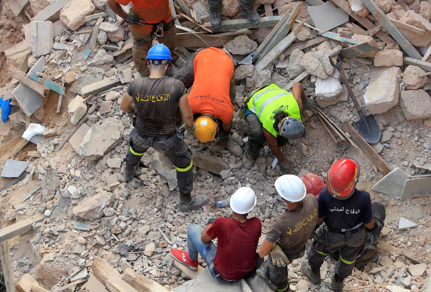 Los miembros del equipo de rescate buscan entre los escombros de los edificios dañados debido a la explosión masiva en Beirut