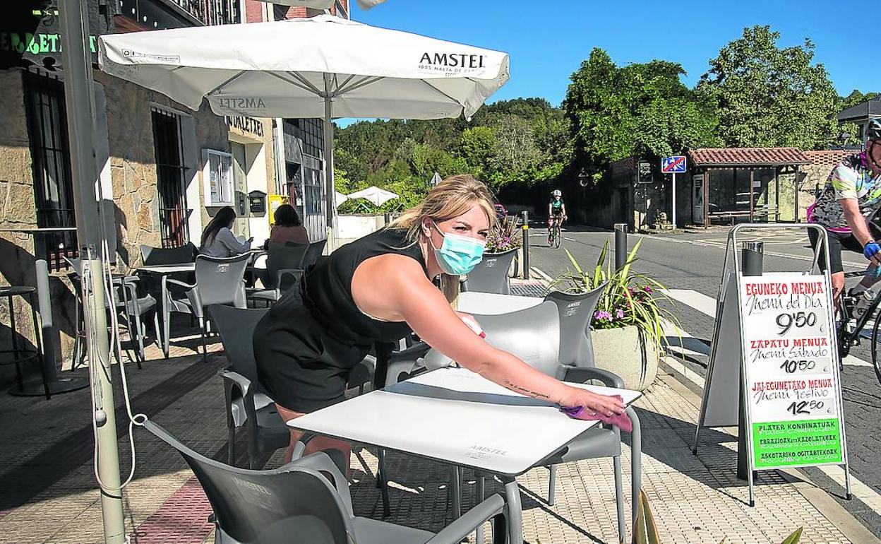 Oihane Arroyo limpia las mesas y las sillas de la terraza de la taberna de Fruiz.