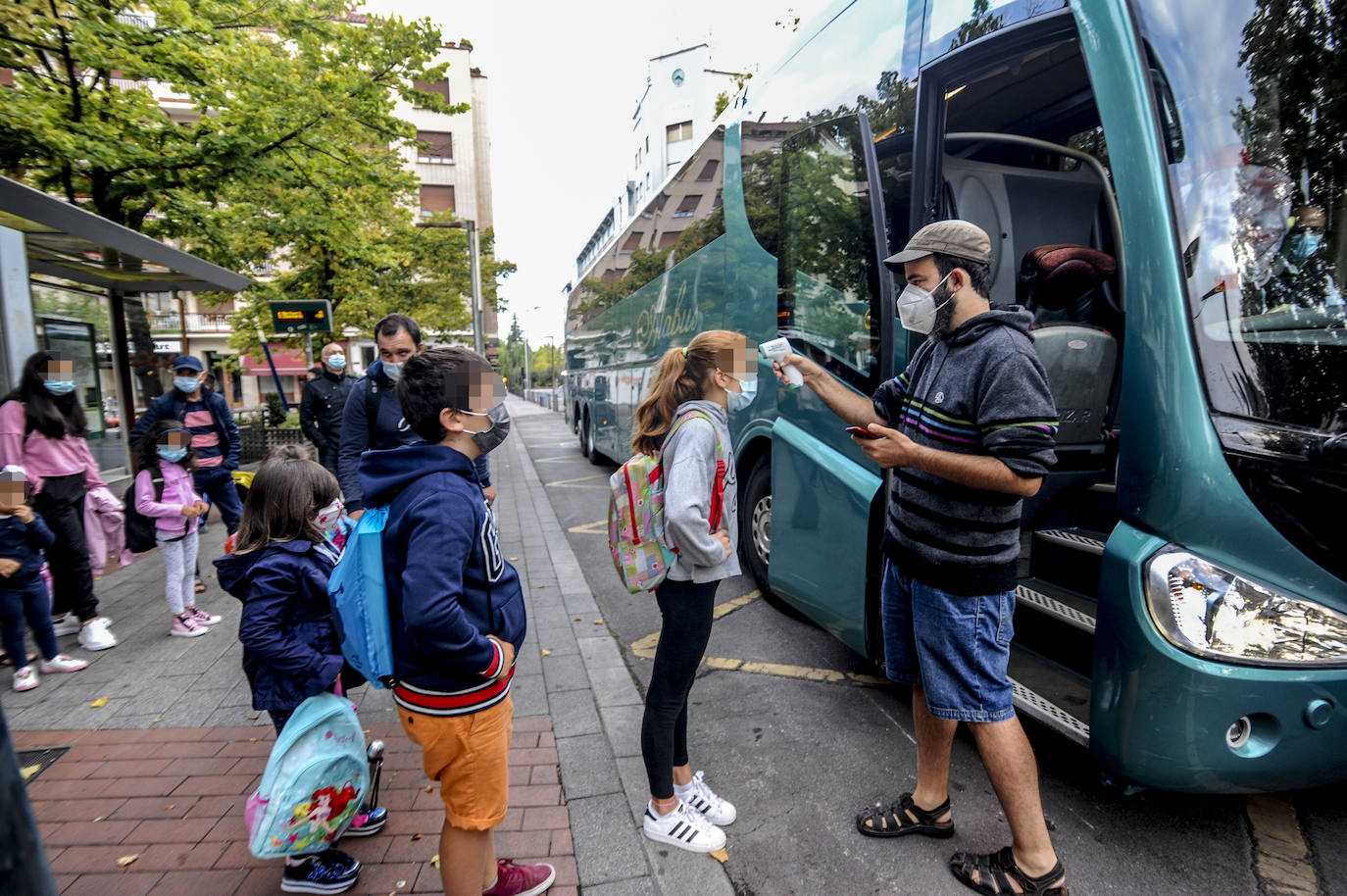 A algunos estudiantes que se trasladan a clase en transporte escolar se les ha tomado la temperatura antes de acceder al autocar que les llevaría a su centro educativo. Todos los alumnos llevaban también puesta su mascarilla. Mientras, sus padres contemplaban la insólita escena.