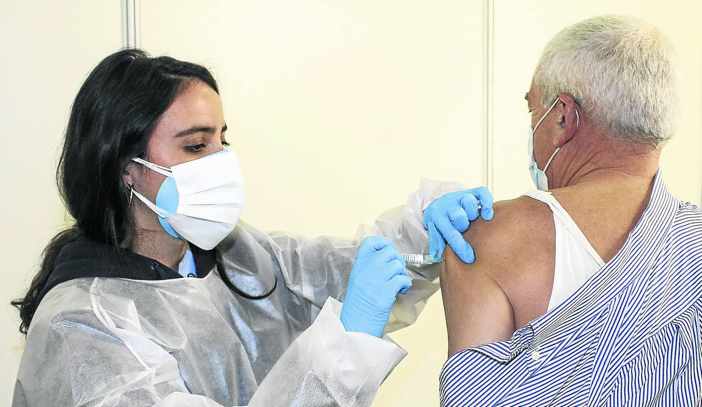 Una enfermera de la OSI Araba inyecta la vacuna de la gripe a un vitoriano en los despachos habilitados en el pabellón Iradier Arena. 