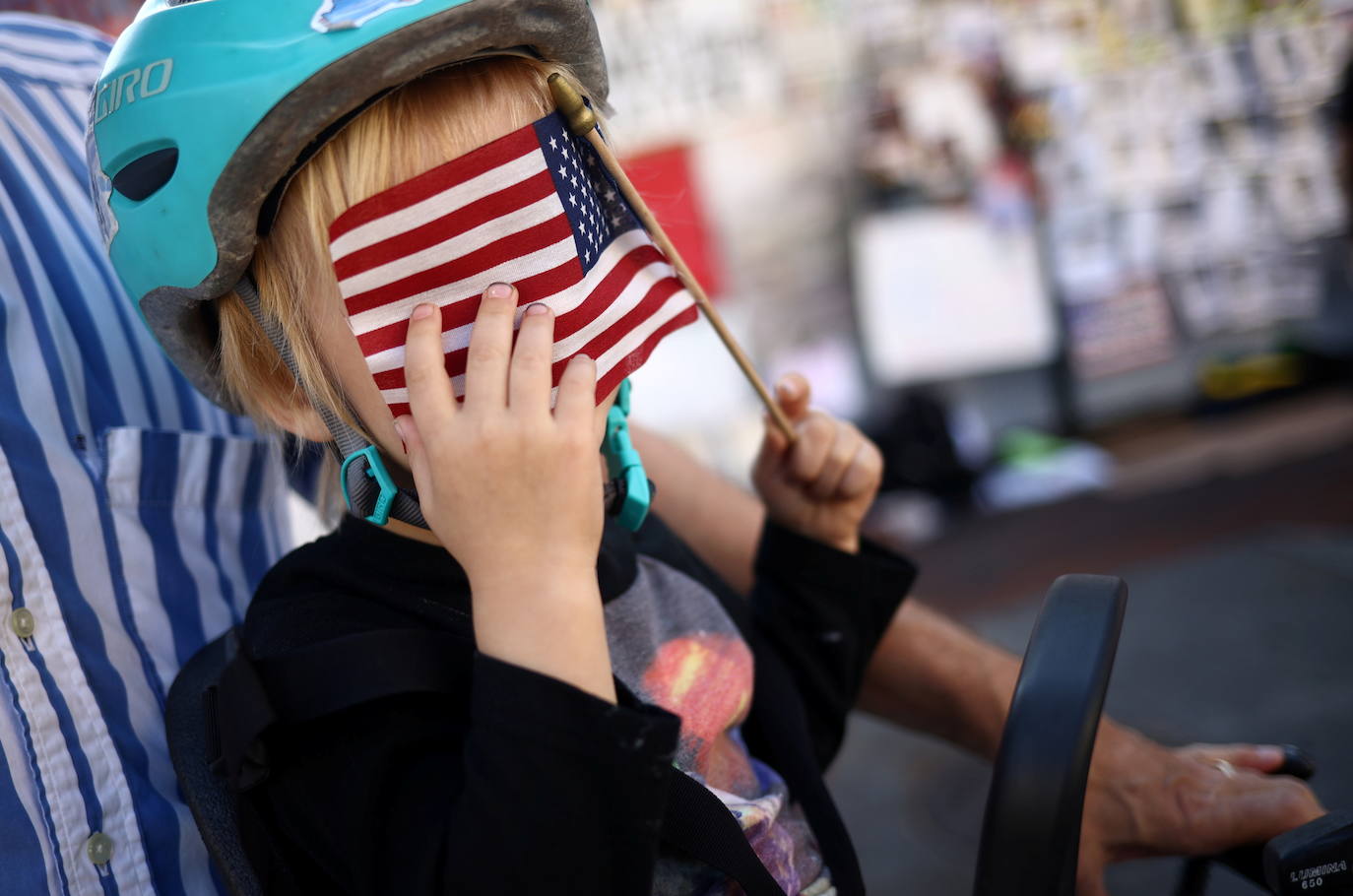 Un niño cubre su rostro con la bandera estadounidense cerca de la Casa Blanca en Washington, DC.