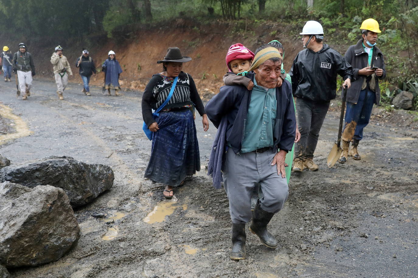 Un hombre carga a un niño a la espalda tras el paso de la tormenta Eta, en San Cristóbal Verapaz.