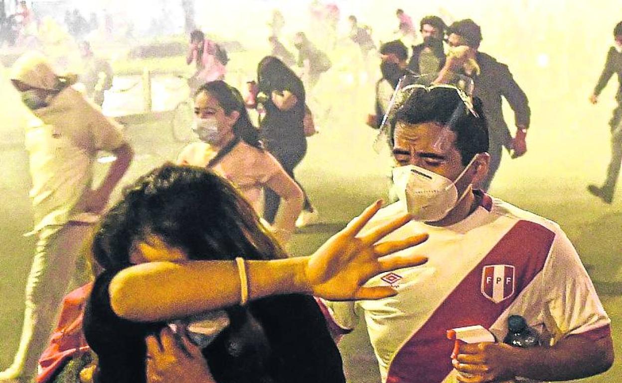 Manifestantes se protegen de los gases lacrimógenos en Lima. 