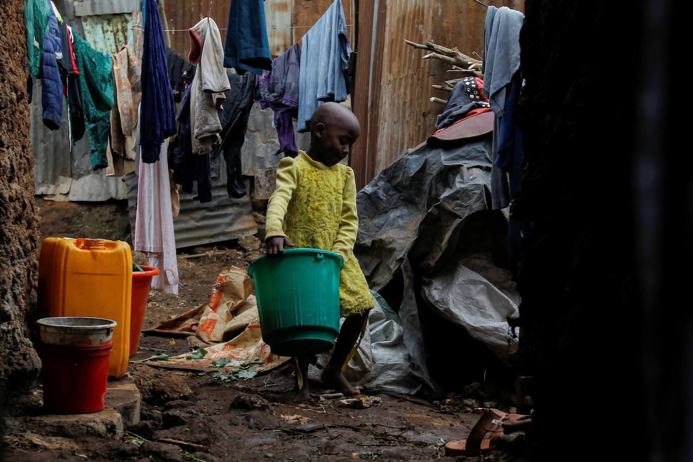 La hermana menor de Jackline Bosibori, Faith Nyakerario, de 5 años, lleva un balde en su casa en la aldea de Lindi dentro de los barrios marginales de Kibera en Nairobi, Kenia.