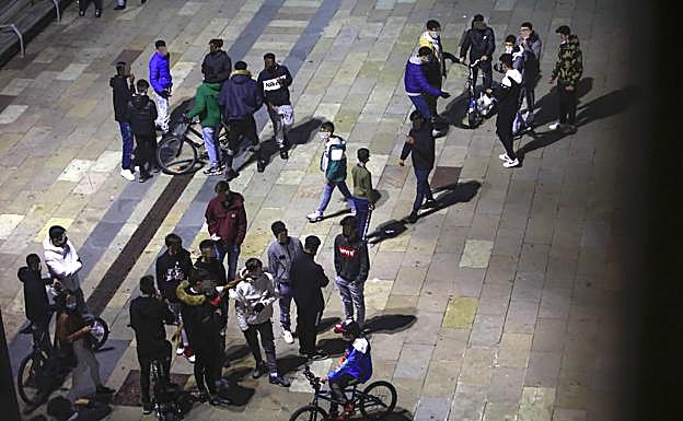 Imagen principal - Jóvenes arremolinados en la plaza de Zumaia y presencia policial en este enclave. Abajo a la derecha, una estampida juvenil tras la aparición de efectivos de la Policía Local. 